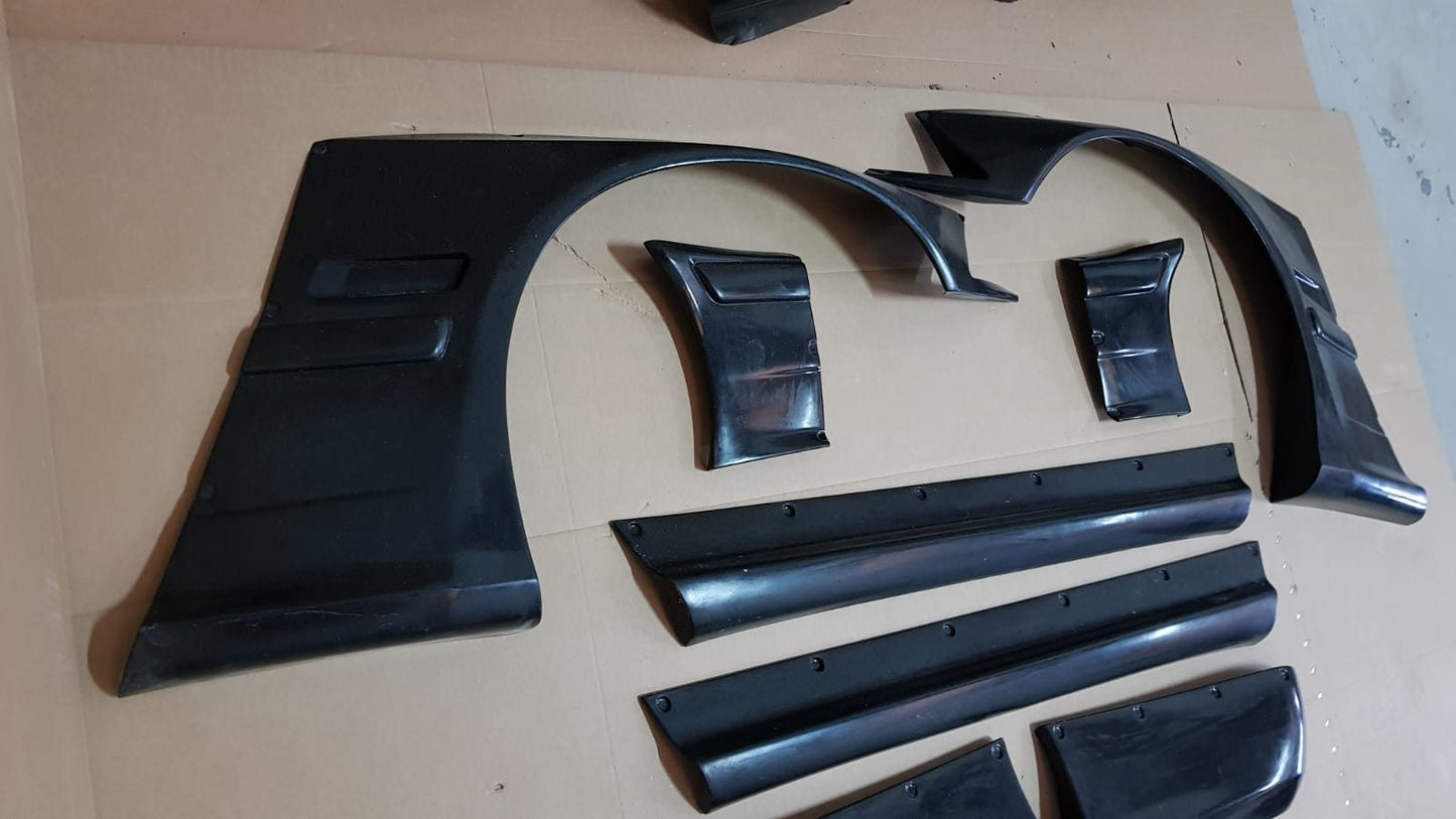 Complete Rocket Bunny widebody kit parts for BMW E36 Coupe including fenders, skirts, and splitters.