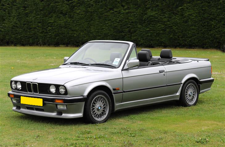 BMW E30 convertible parked on a lawn, featuring a Hartge H23 style front bumper add-on.