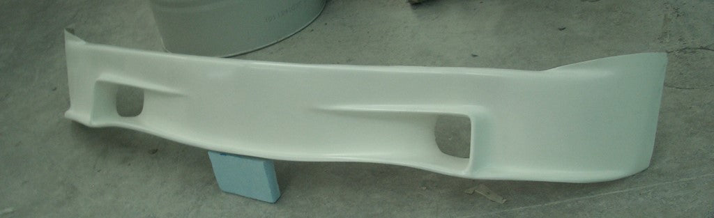 Angled view of a racing-style front lip for BMW 2002, highlighting aerodynamic contours and fog light openings.