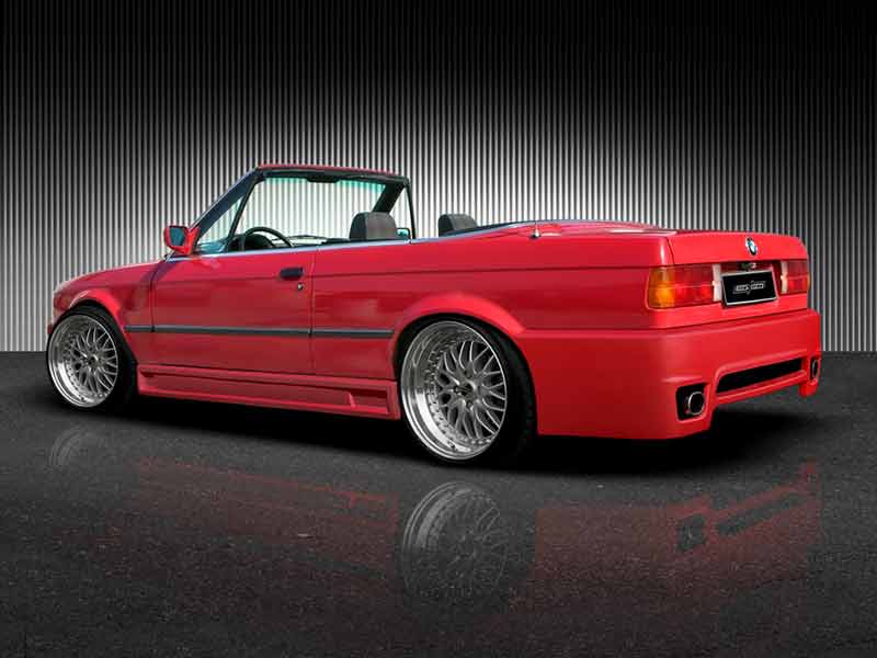 Back side view of red BMW E30 convertible equipped with PLUS side skirts, enhancing the car’s sporty appearance with a lowered profile and wider stance.
