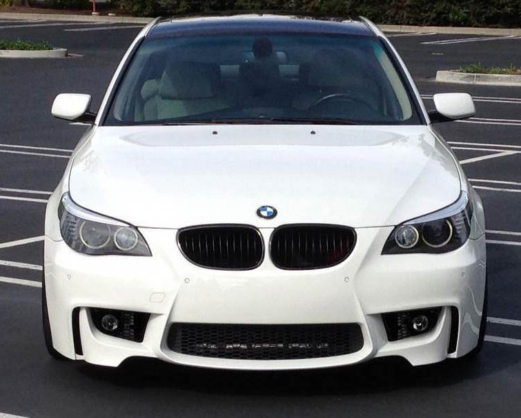 BMW 5 Series E60/E61 with 1M Look front bumper, painted in white, featuring integrated fog lights, large air intakes, and black kidney grilles for a sporty upgrade.