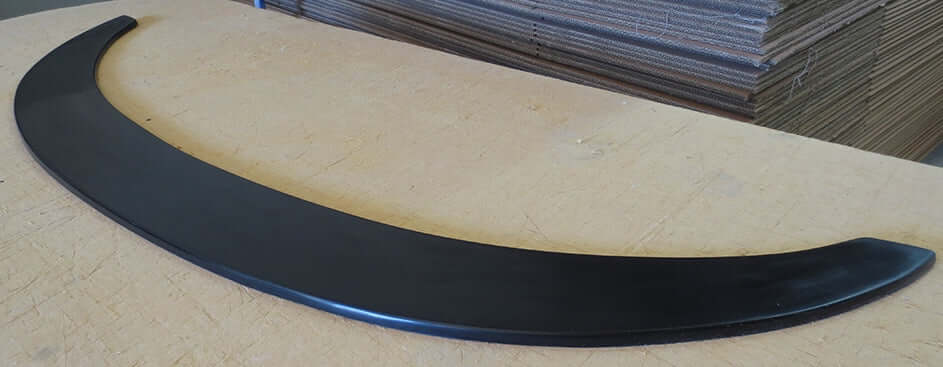 FRONT BLADE LIP BMW E90 M4 LOOK style bumper, black component displayed on workshop table.