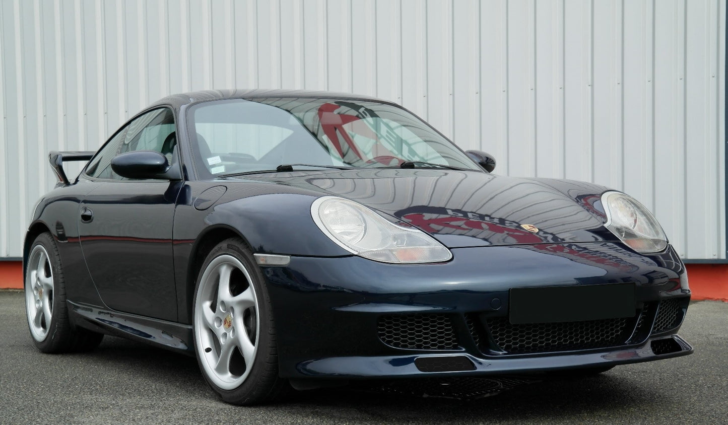 Dark blue Porsche 911 (996 Phase 1) with GT3 Look front bumper, featuring large mesh air intakes, splitters, silver five-spoke wheels, and a rear wing visible in the background.