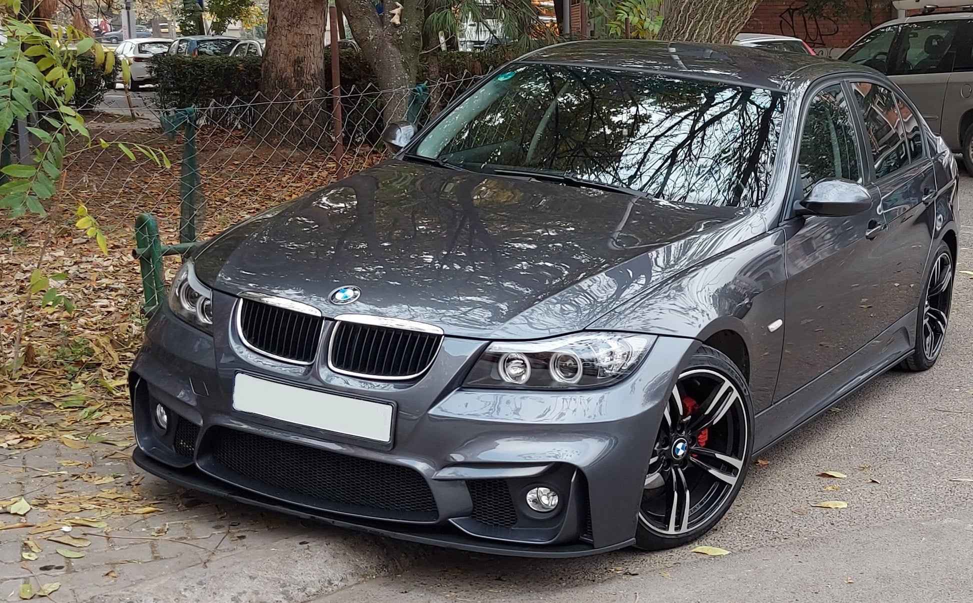 Grey BMW E90 with M4 style front bumper and front lip blade, aftermarket wheels and lowered stance