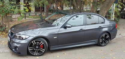 BMW E90 sedan with front blade lip spoiler installed on M4 style bumper, parked on street
