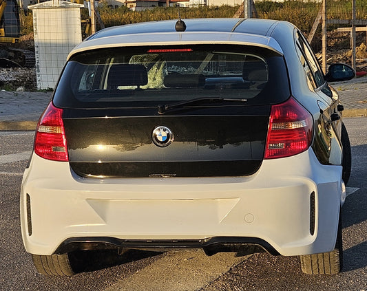 Rear bumper BMW 1 Series E81/E87 M2 Look installed, shown from rear view, featuring wide contours and black diffuser styling.