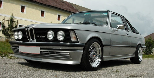 BMW E21 equipped with a BBS style front lip spoiler, parked in front of a residential building.