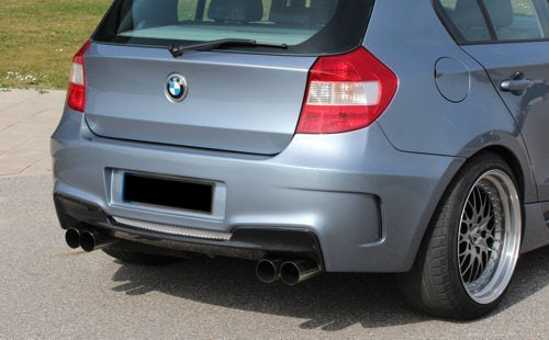 Rear view of a BMW 1 Series E81/E87 fitted with a 1M look rear bumper in grey, featuring quad exhaust outlets.
