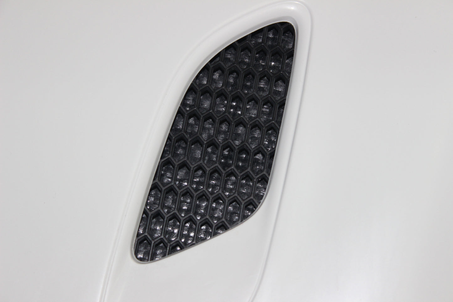 Close-up of one of the bonnet air vents for BMW 1 Series E81/E82/E87/E88 M1, with hexagonal mesh pattern.
