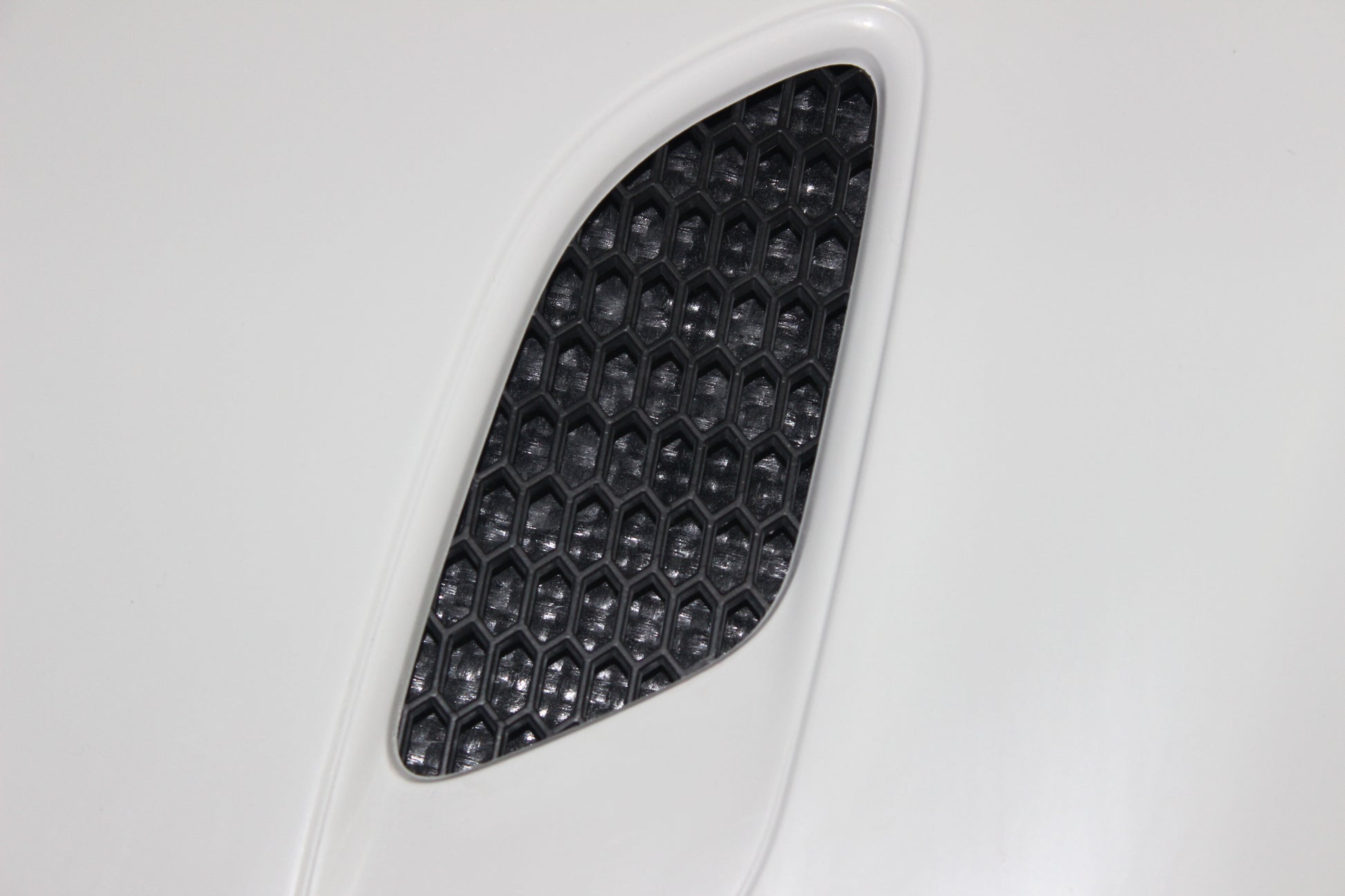 Close-up of one of the bonnet air vents for BMW 1 Series E81/E82/E87/E88 M1, with hexagonal mesh pattern.