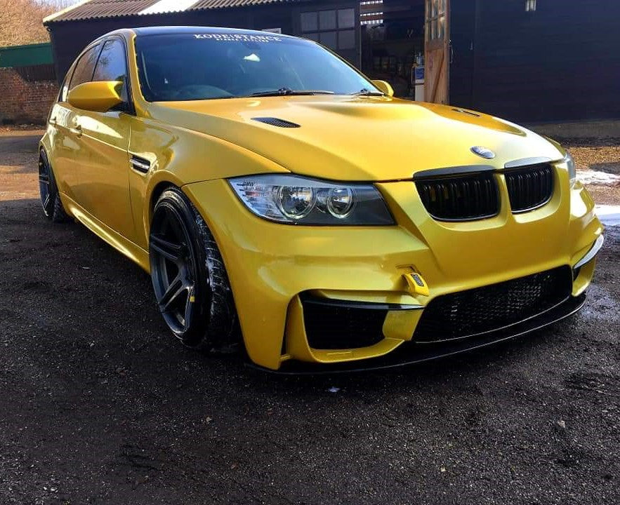 Gold BMW E90 with aggressive M4 style bumper and front lip blade, fitted with wide stance wheels