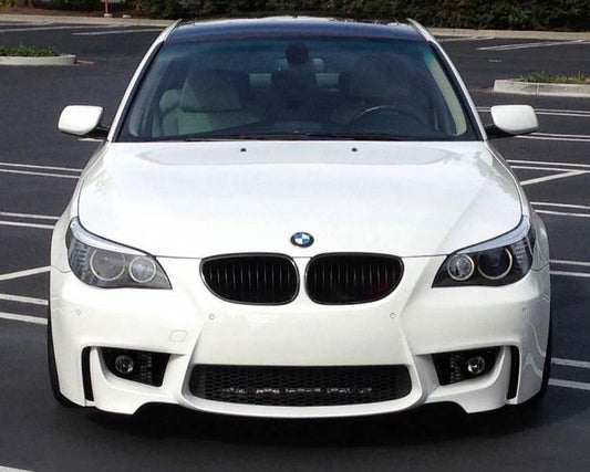 BMW 5 Series E60/E61 with 1M Look front bumper, painted in white, featuring integrated fog lights, large air intakes, and black kidney grilles for a sporty upgrade.