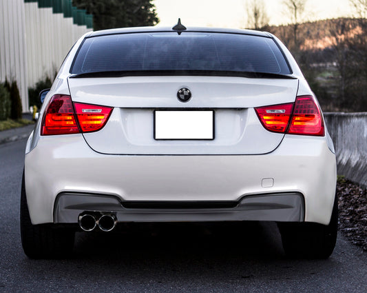 Rear view of a white BMW 3 Series E90 with 1M Look rear bumper, featuring quad exhaust tips and sporty diffuser design.